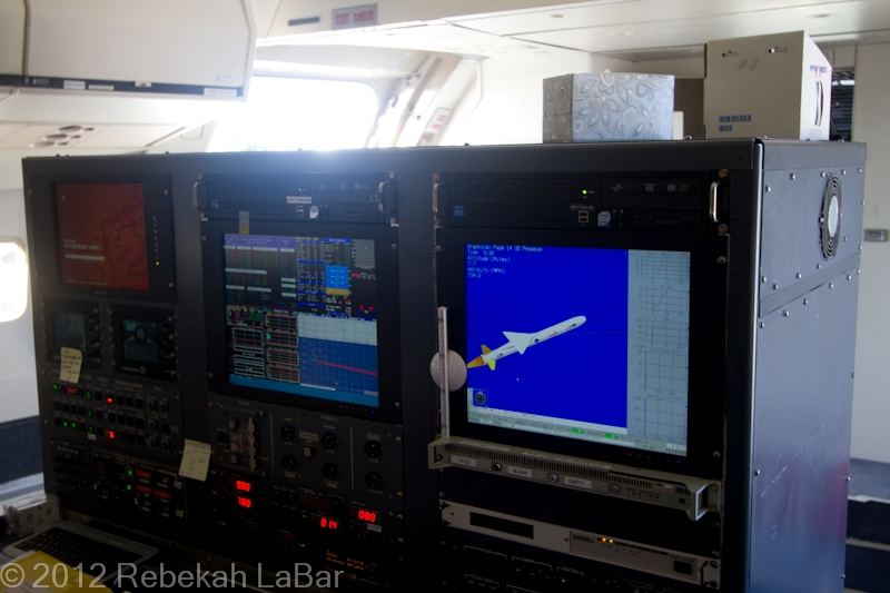 Where first class seating would be, they had a large instrument panel set up for controlling the rocket and deployment of the satellite. The screen on the right is showing a simulation.